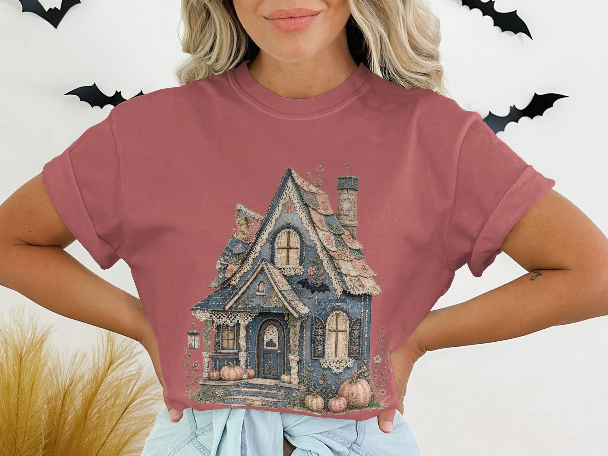 Pink t-shirt with a whimsical blue house illustration and pumpkins.