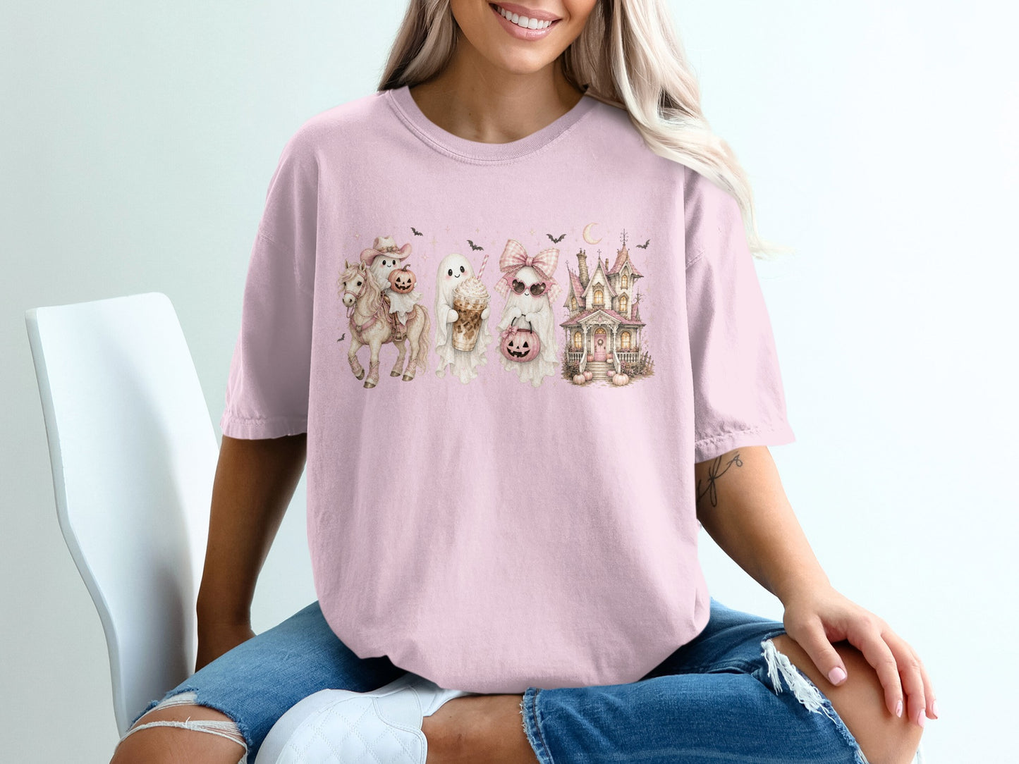 Pink t-shirt with a Halloween graphic of a horse, ghosts, and haunted house.