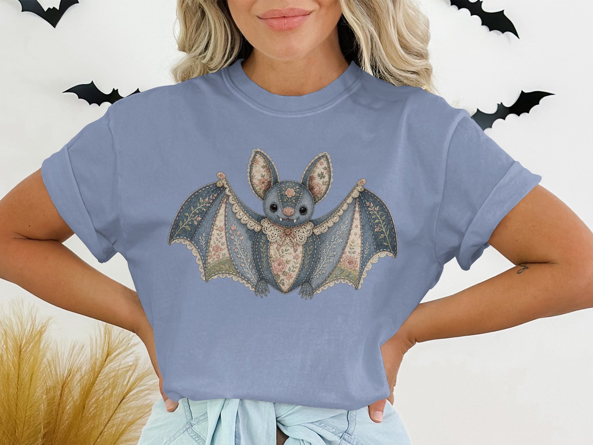 Bat graphic t-shirt with floral and lace details on a faded blue tee.