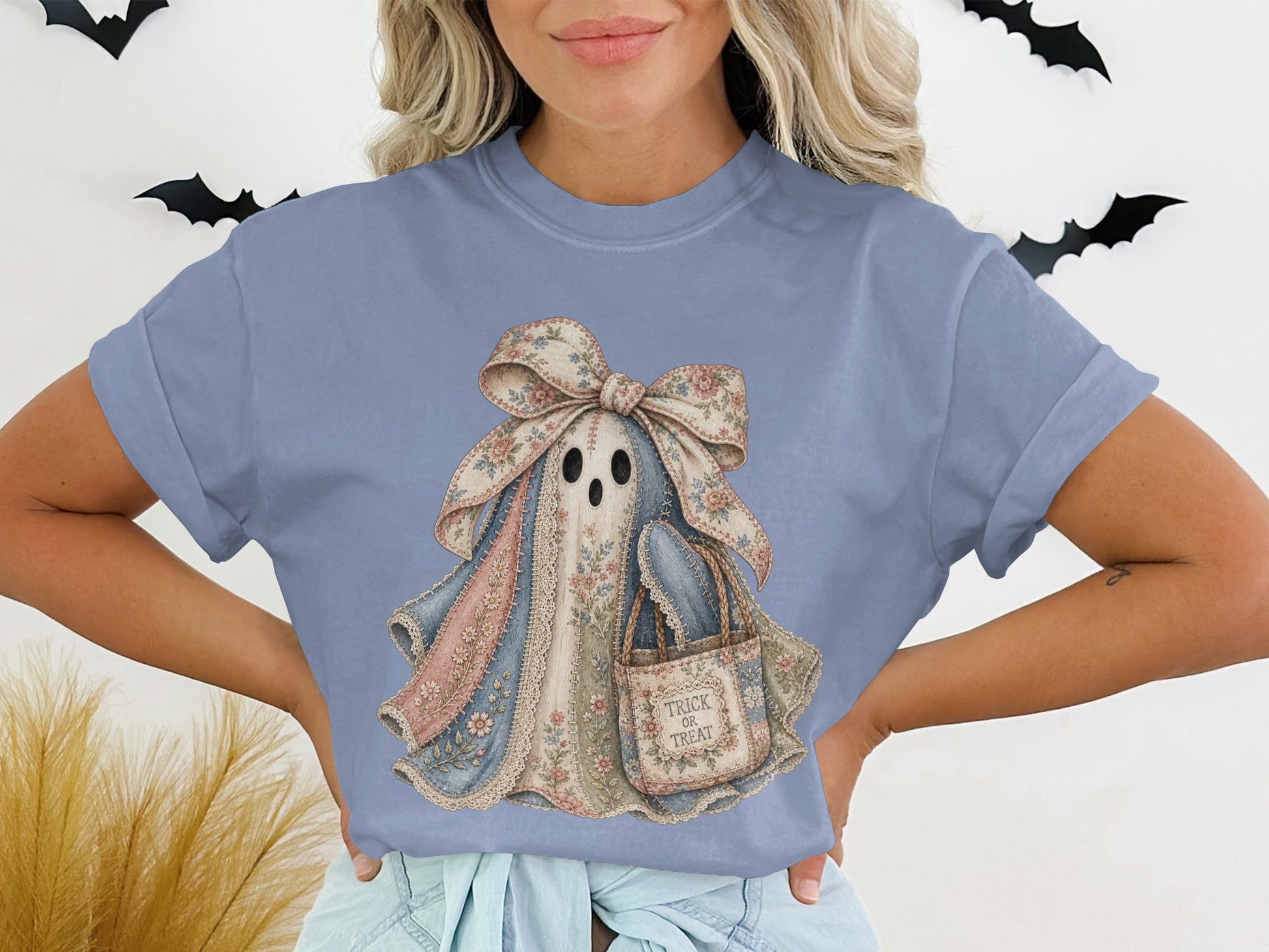 Ghost graphic with floral bow and "Trick or Treat" bag on a light blue t-shirt.