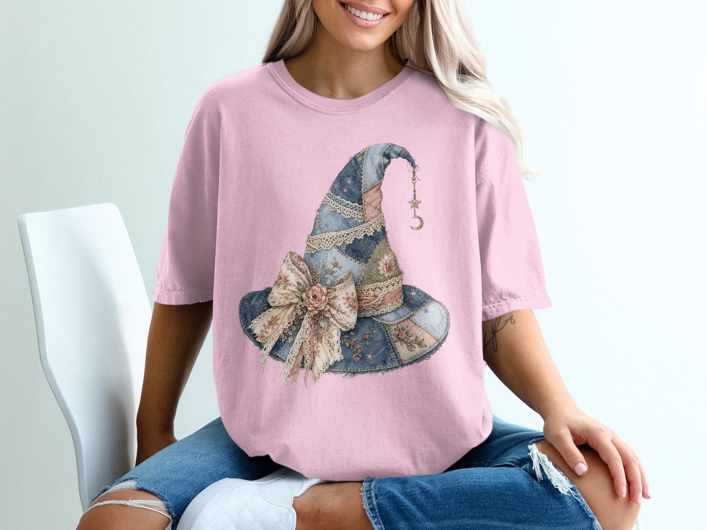 Pink crewneck t-shirt with a patchwork witch hat graphic and moon and star charm.