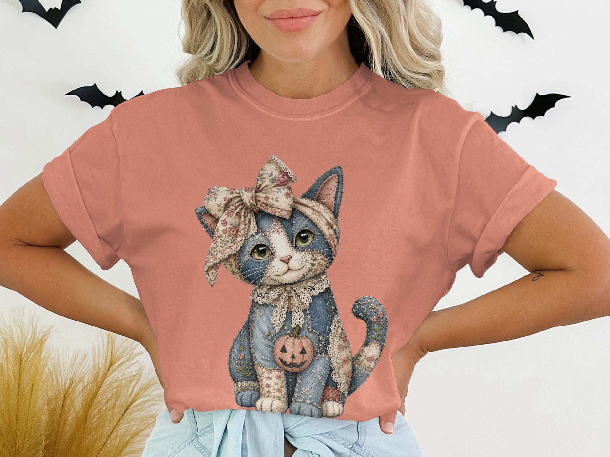T-shirt with a stitched cat wearing a floral bow and holding a jack-o'-lantern.