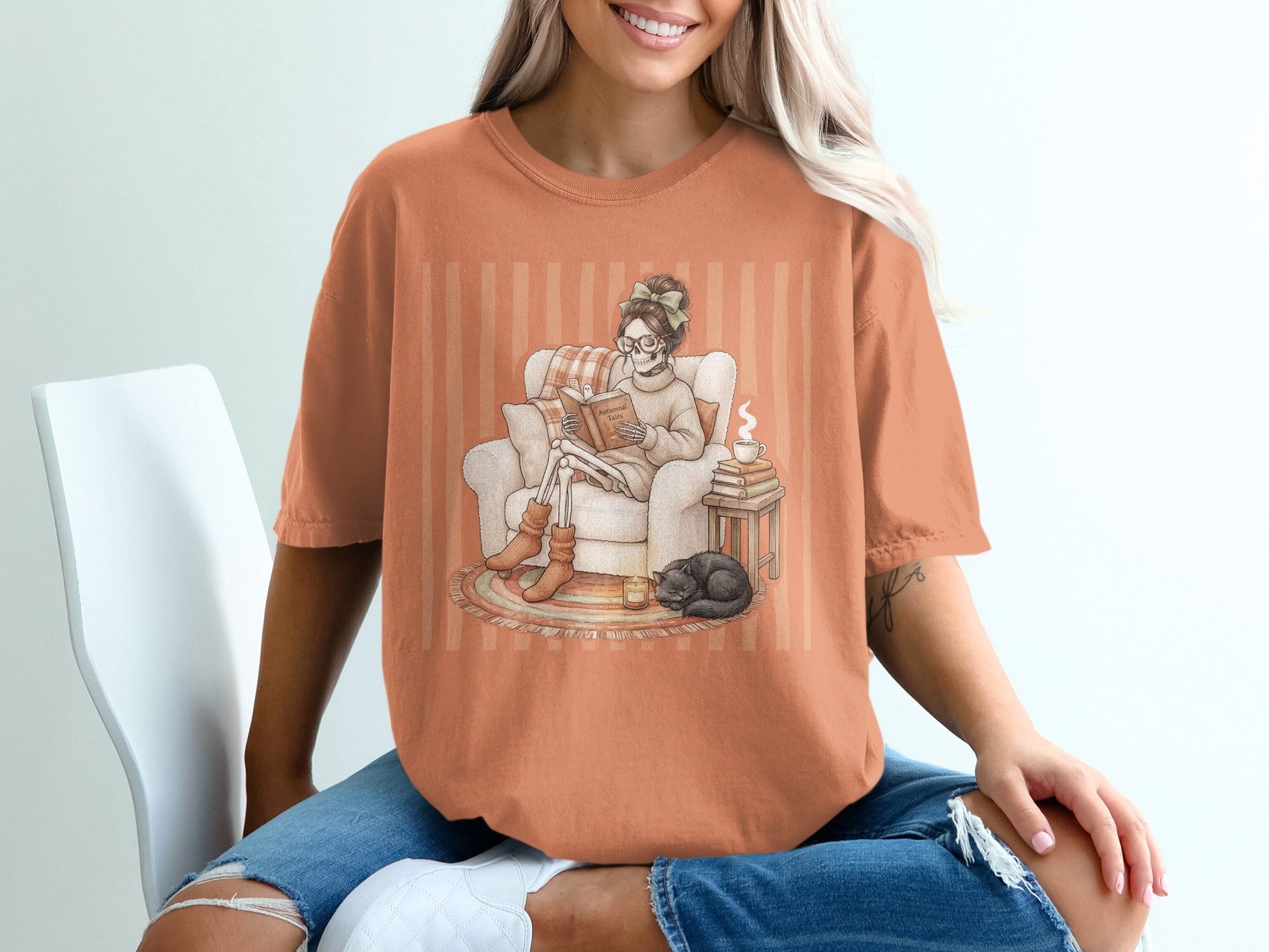 Skeleton reading with cat and coffee on an orange striped shirt.