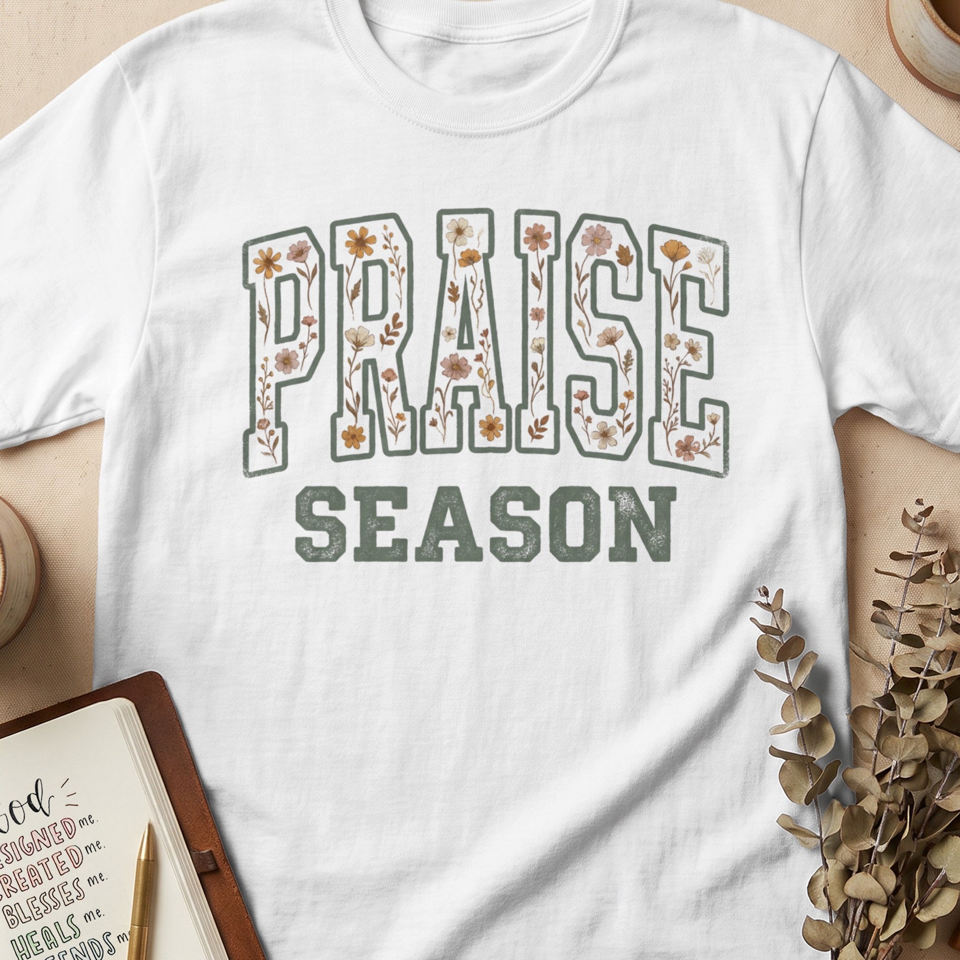 White t-shirt with "PRAISE SEASON" text in floral, vintage lettering.