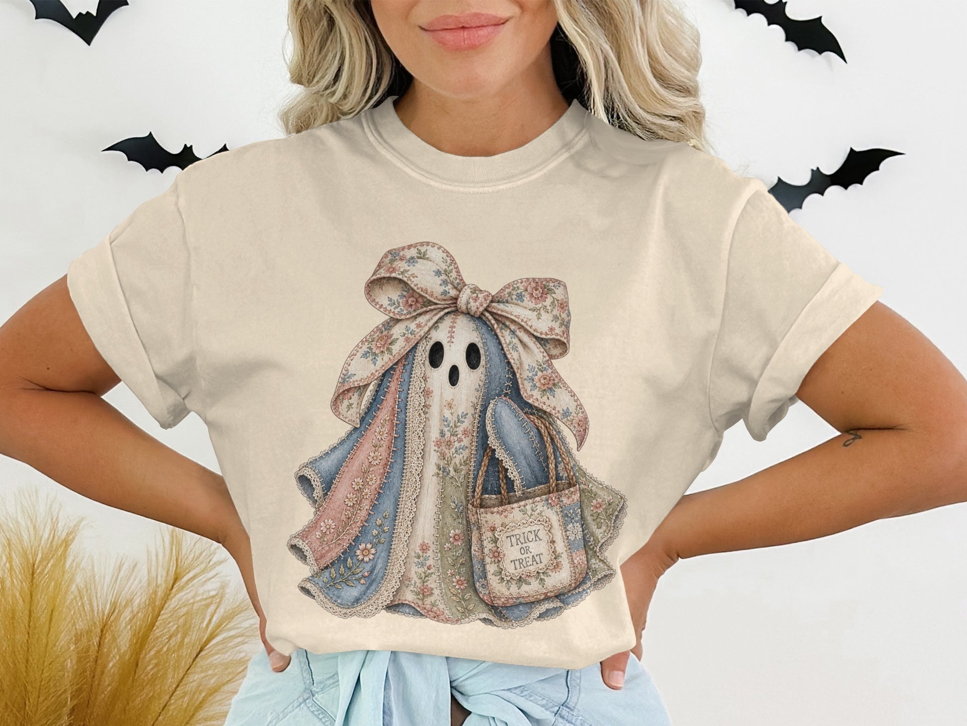 T-shirt graphic of a patchwork ghost wearing a floral bow and carrying a trick-or-treat bag.
