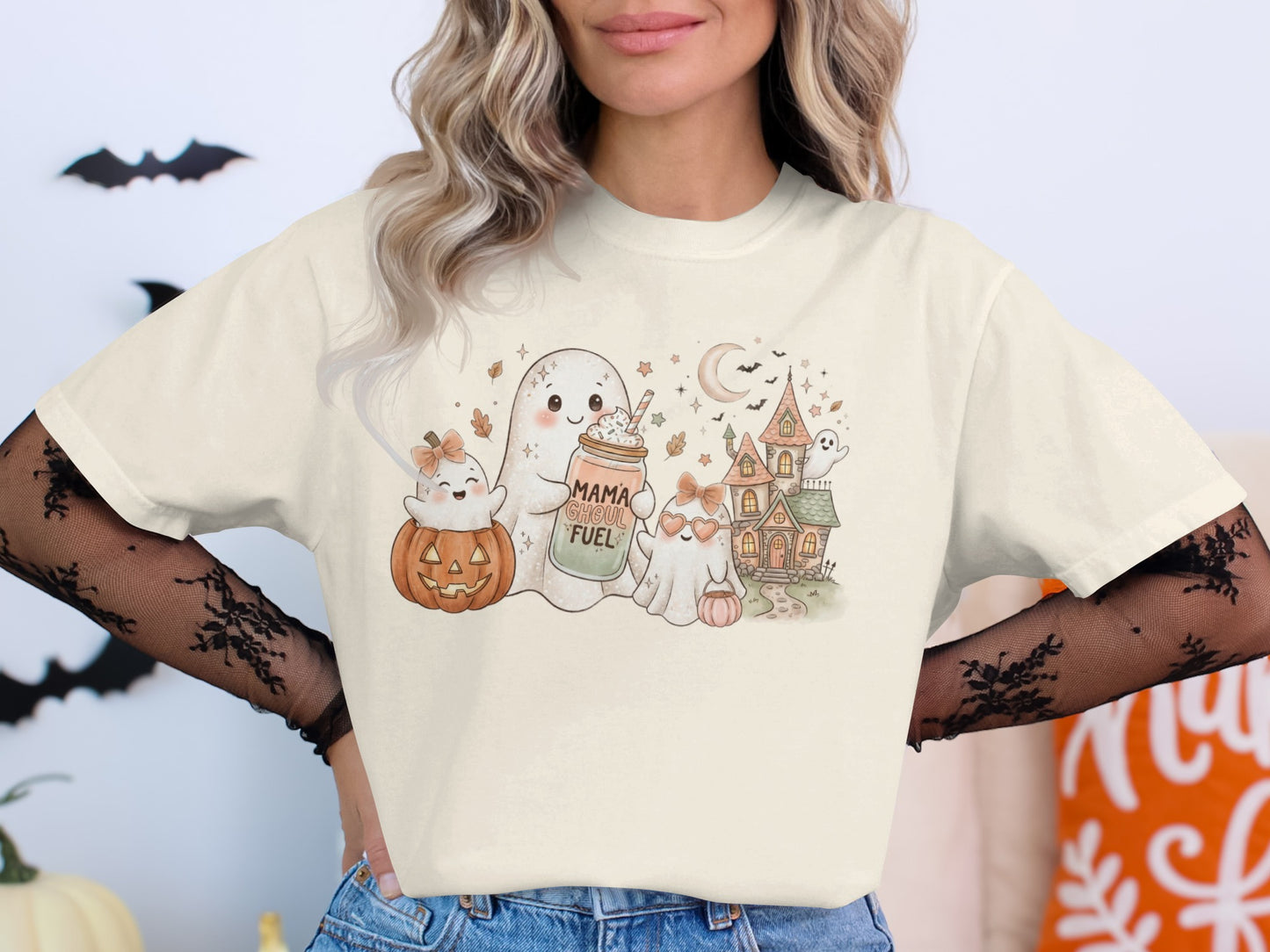 Cute ghosts and "Mama Ghoul Fuel" text on a cream t-shirt with Halloween scene.