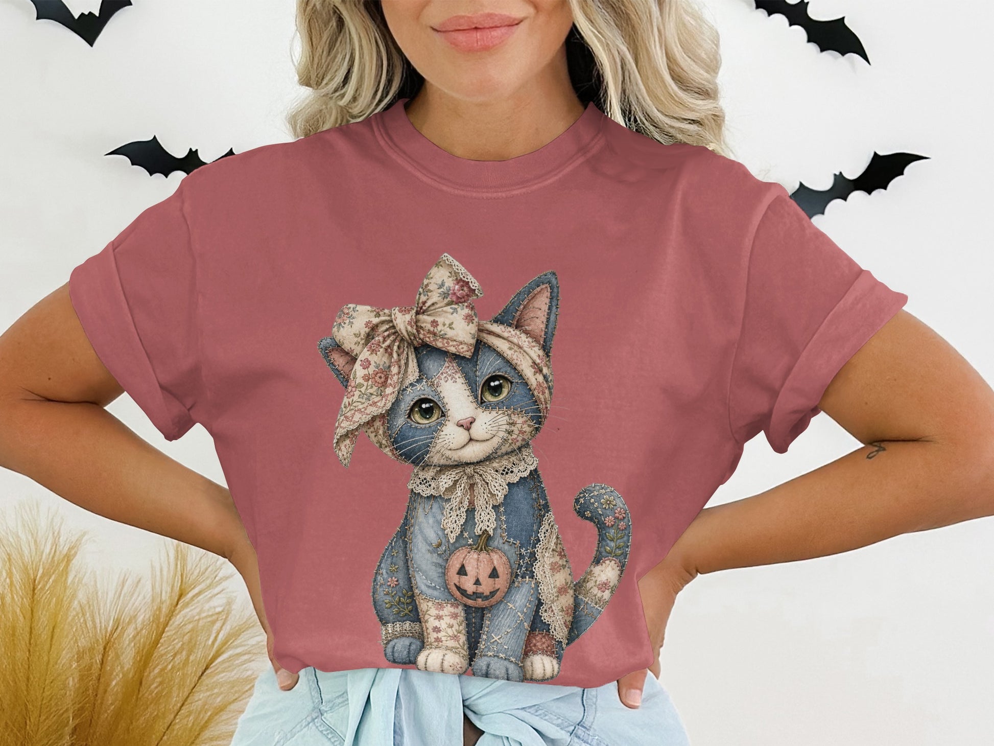 T-shirt with jack-o'-lantern pumpkin print on a patchwork cat with a floral bow.