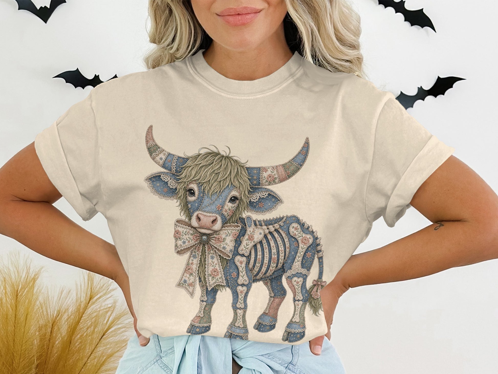 T-shirt featuring a decorative skeleton highland cow with floral accents and bow.