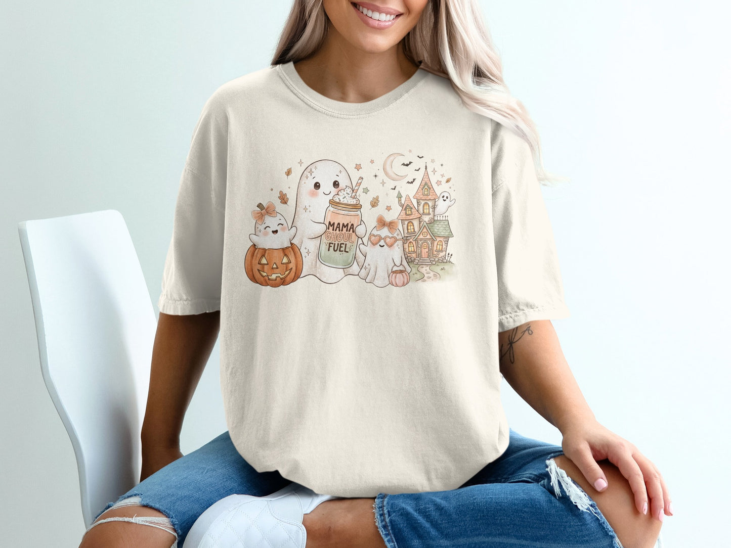 Ghost with jar labeled "Mama Ghoul Fuel", pumpkin, and haunted house graphic on a t-shirt.