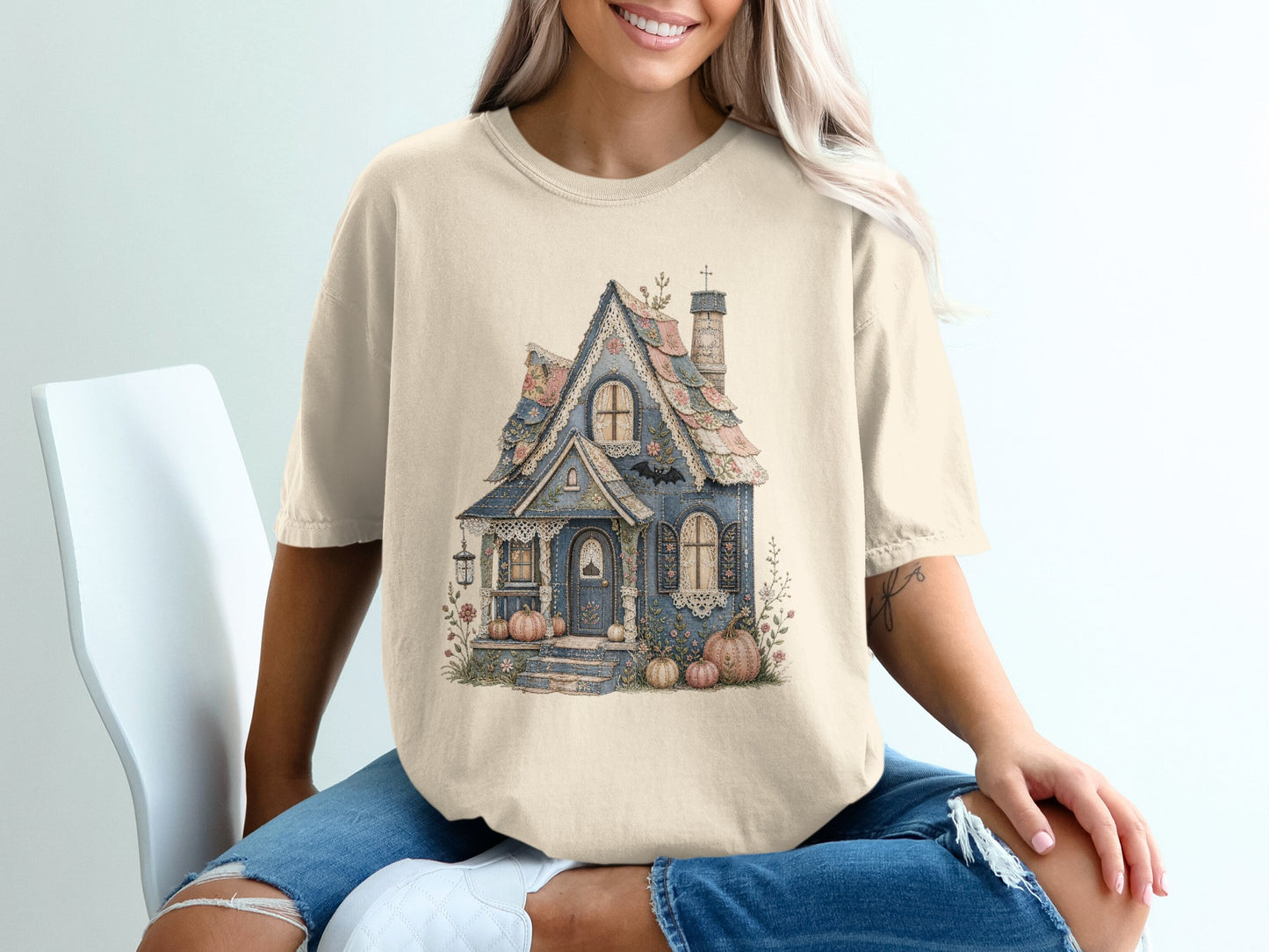 T-shirt with a faded blue cottage graphic surrounded by pumpkins and floral accents.