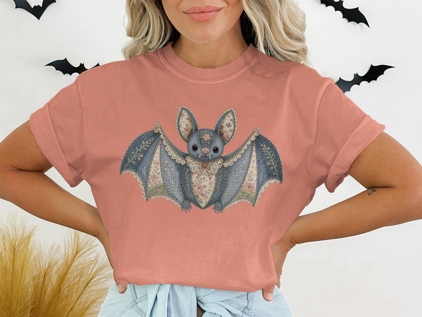 Pink t-shirt with a distressed denim-style bat graphic featuring floral accents and lace trim.