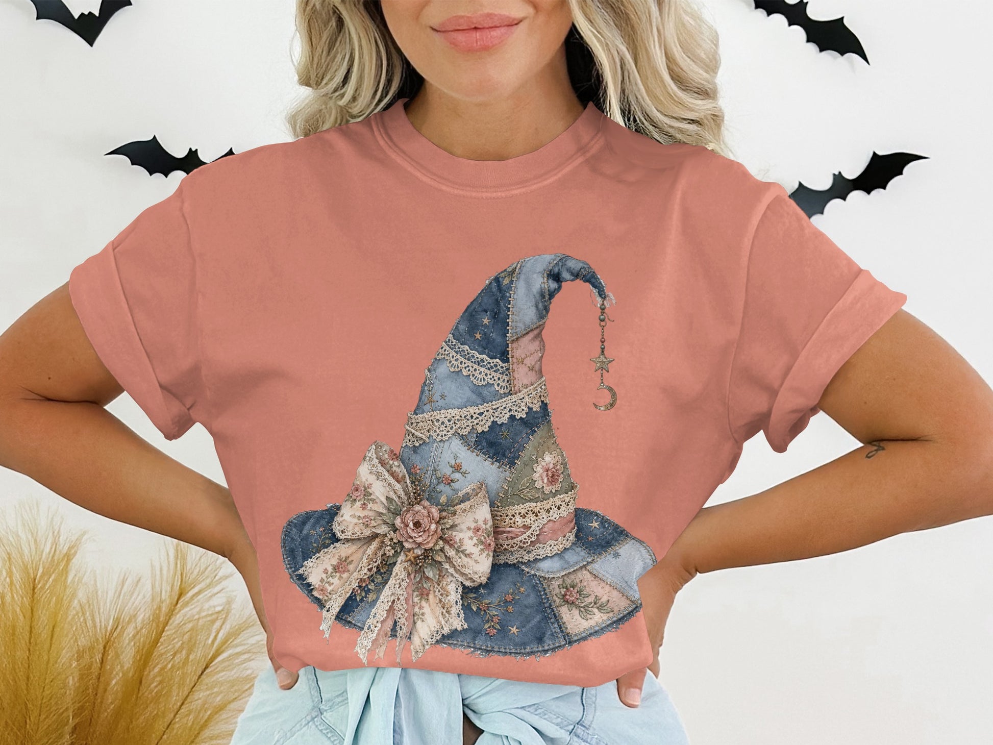 T-shirt with a watercolor witch hat graphic featuring a bow and moon charm.