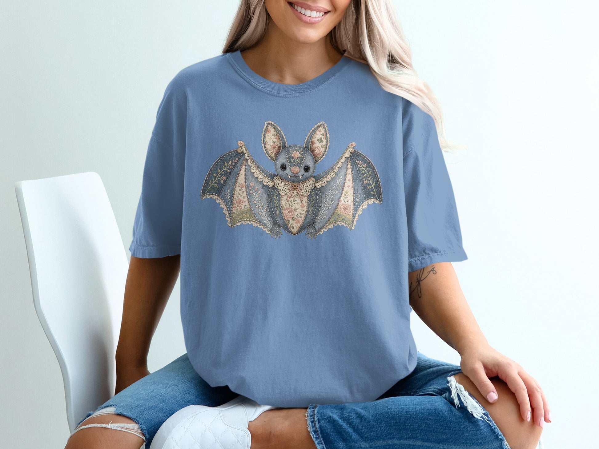 Blue t-shirt with a decorative bat graphic featuring floral patterns and lace trim.
