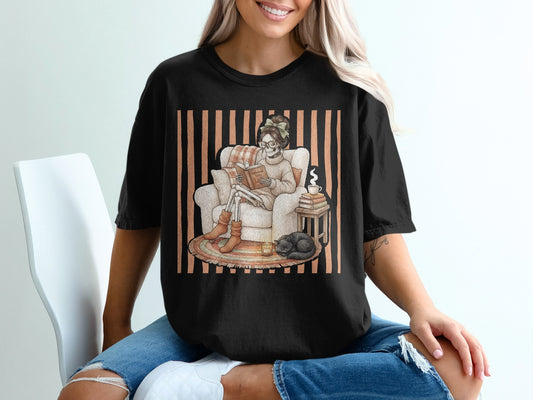 Skeleton reading "Autumn Tales" in armchair with cat, candle, and book stack.