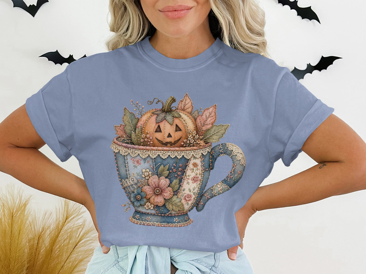 Jack-o'-lantern in a vintage teacup surrounded by autumn leaves and flowers.