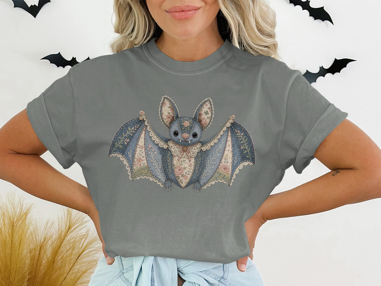 T-shirt graphic of a patched denim bat with lace trim and floral accents.