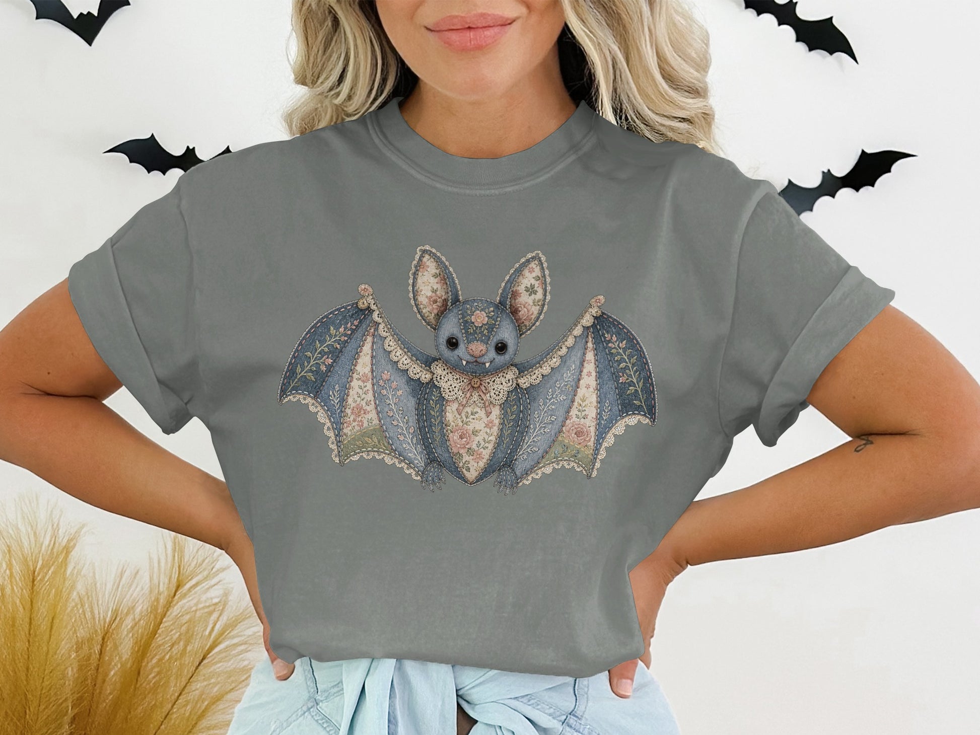 T-shirt graphic of a patched denim bat with lace trim and floral accents.