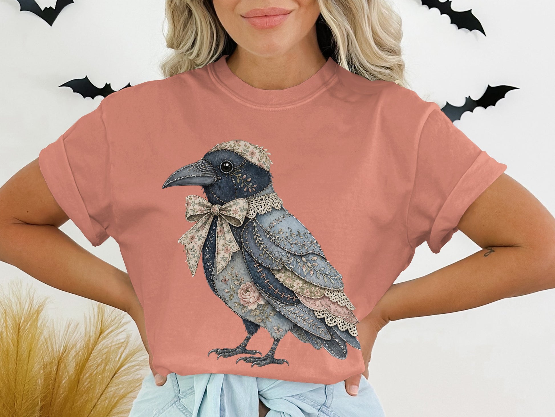 Illustration of a crow with a floral bow on a coral t-shirt with black bats.