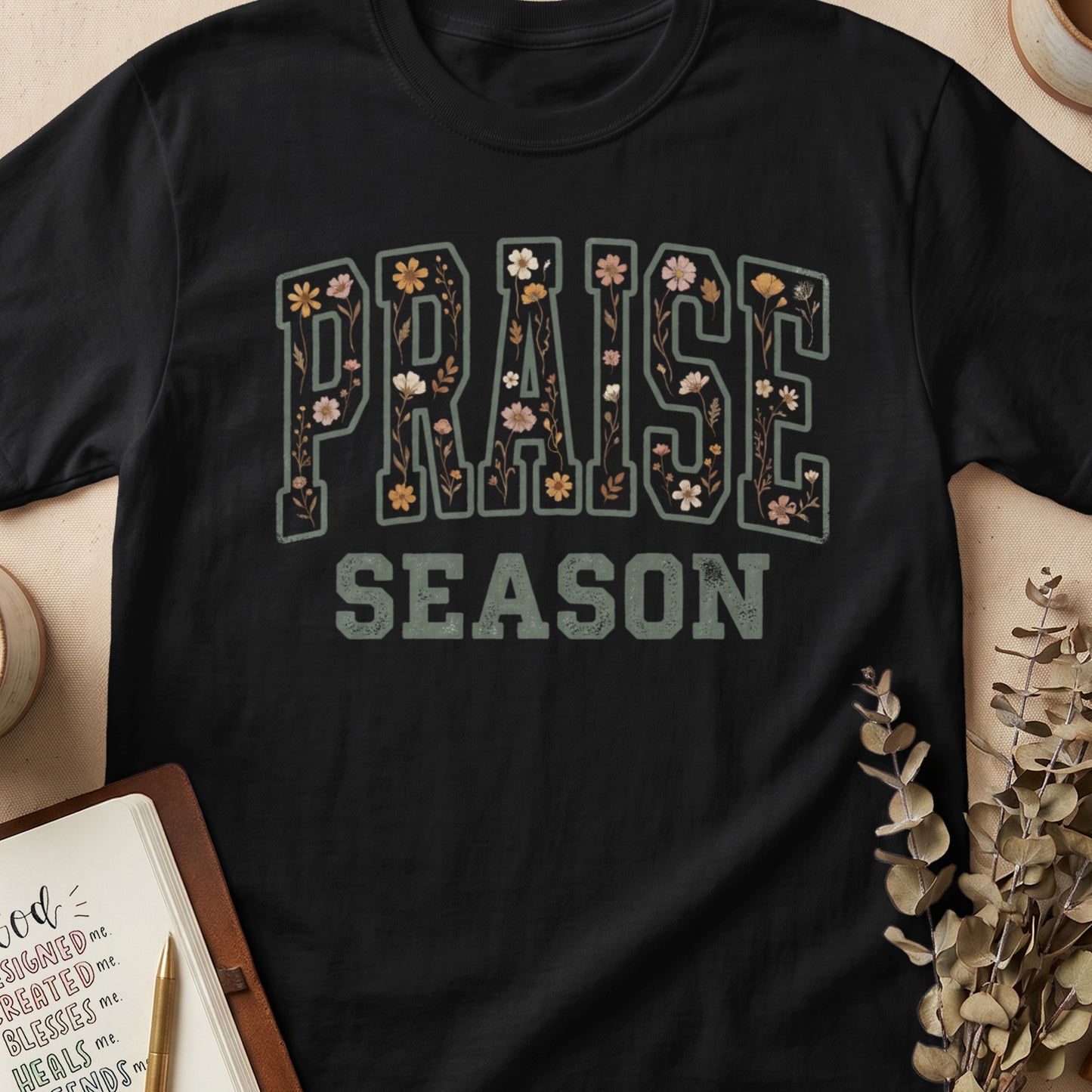 Black t-shirt with "PRAISE SEASON" text adorned with floral illustrations.