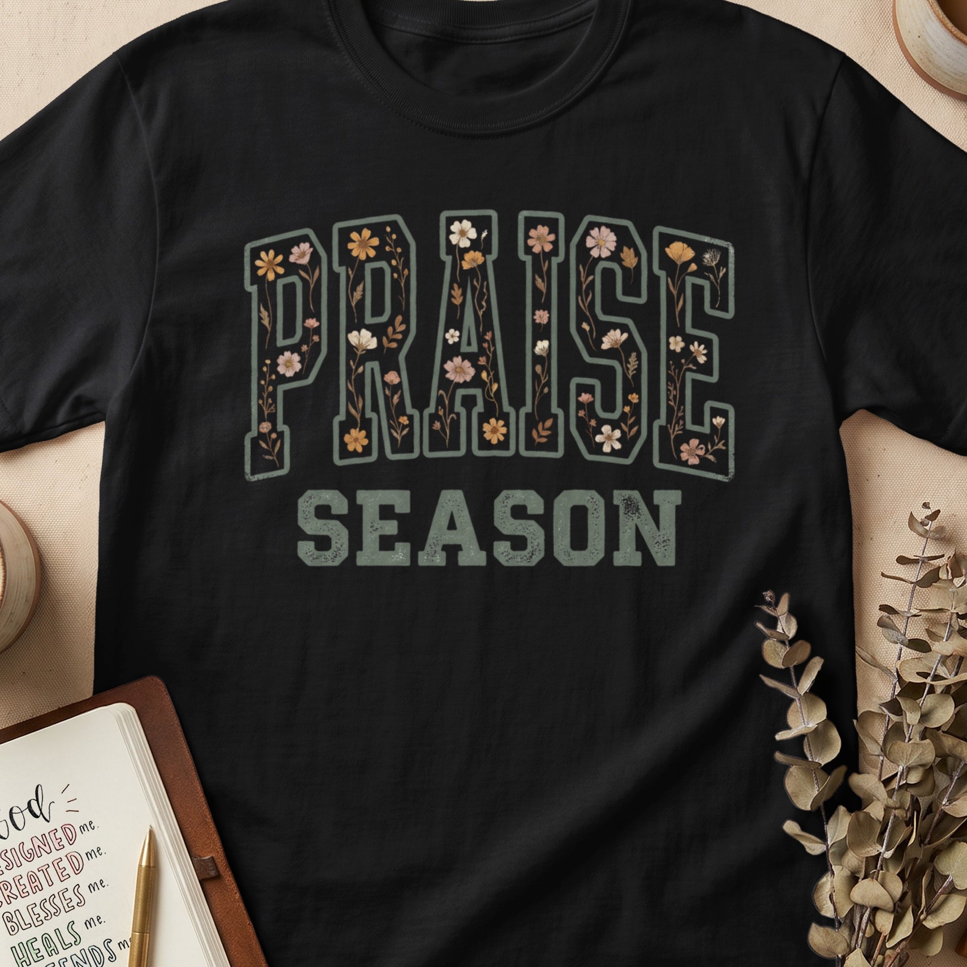 Black t-shirt with "PRAISE SEASON" text adorned with floral illustrations.