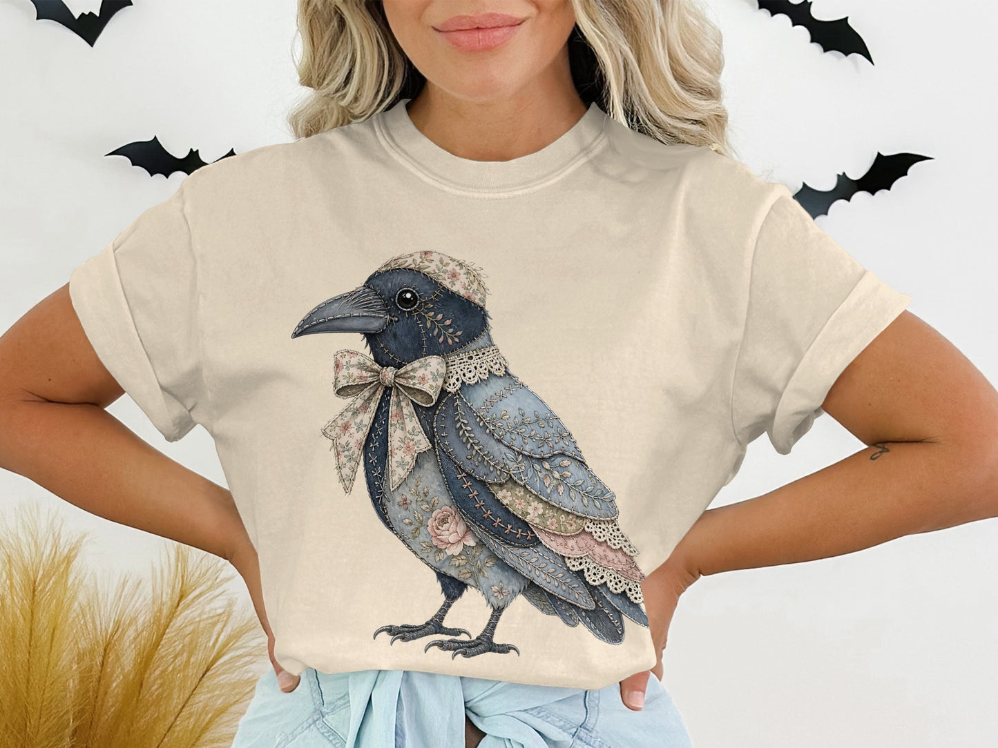 T-shirt with a blue bird wearing a floral bow and hat, against a white background with bats.