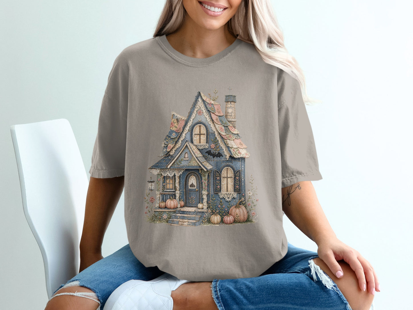 T-shirt graphic of a whimsical blue house with floral accents and pumpkins.