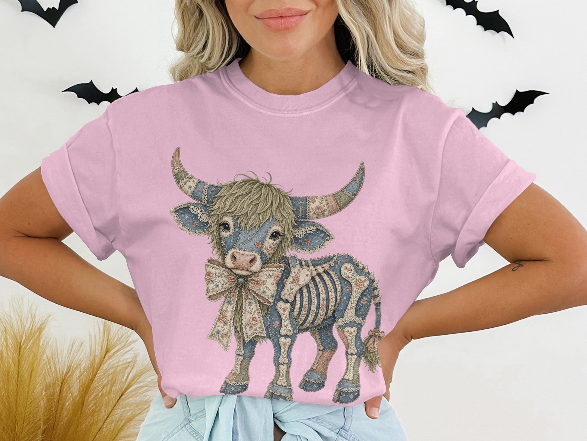 Graphic tee with a skeleton cow wearing a floral bow on a pink shirt.