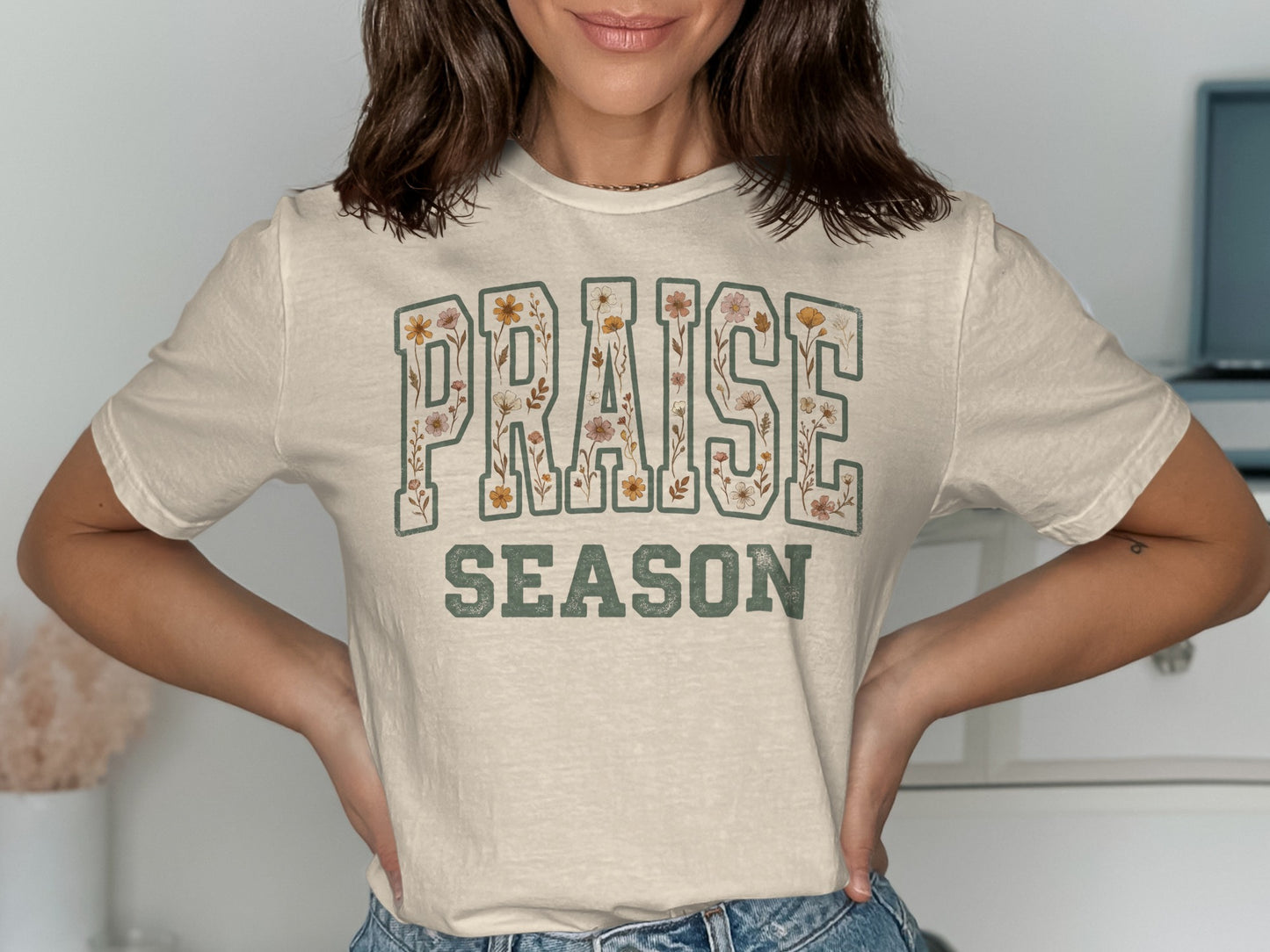 Cream t-shirt with "PRAISE SEASON" text decorated with floral patterns.