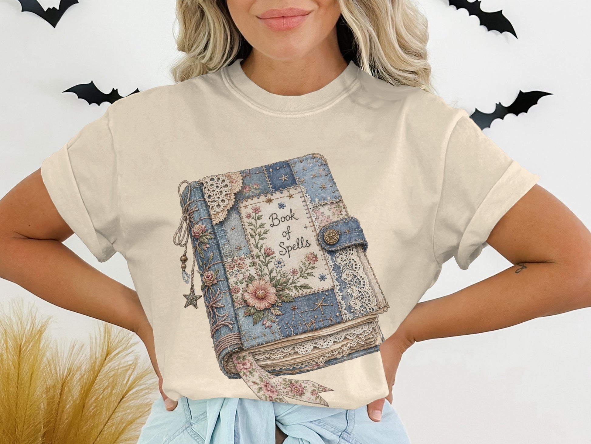 T-shirt graphic of a patchwork book with "Book of Spells" in floral lettering.