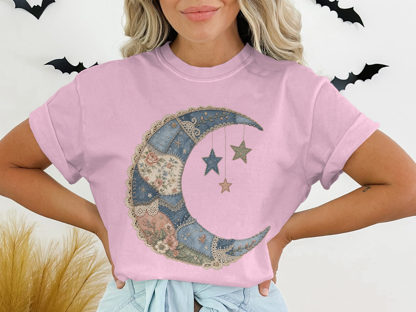 Pink t-shirt with a crescent moon and stars graphic made of patchwork fabric.