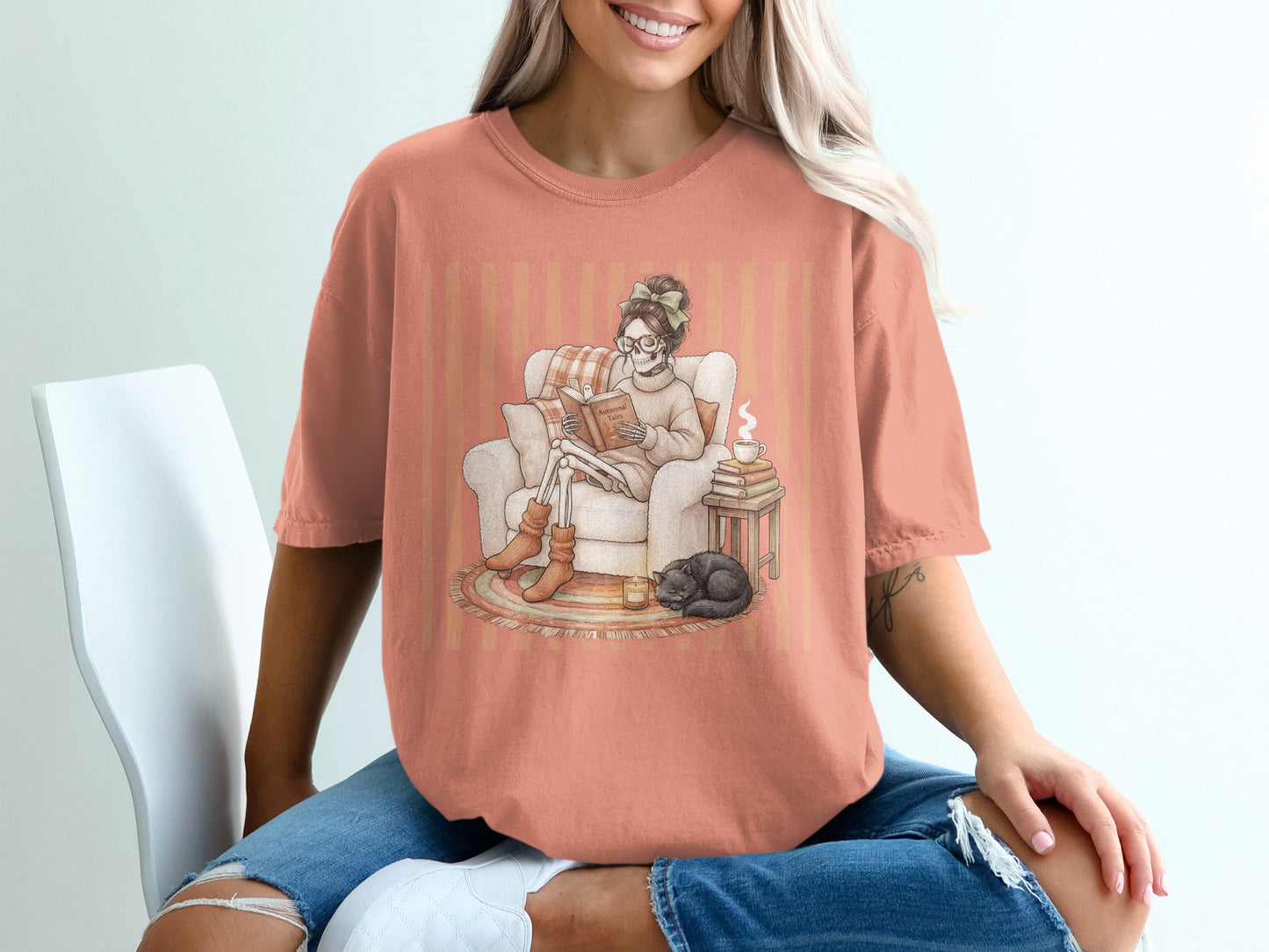Skeleton reading a book in armchair with cat and coffee on peach striped shirt.