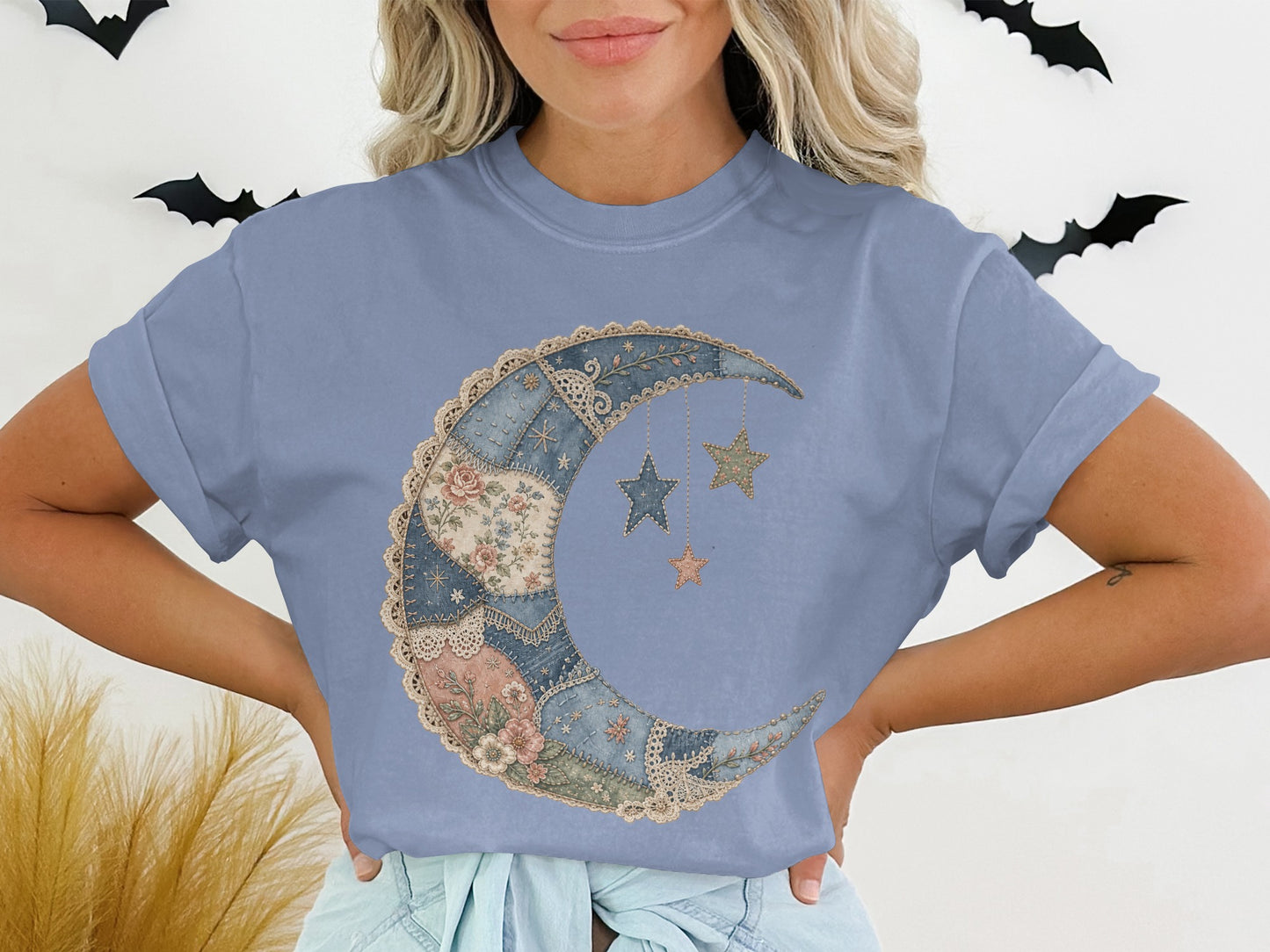 Patchwork moon and stars graphic on a light blue short-sleeve t-shirt.
