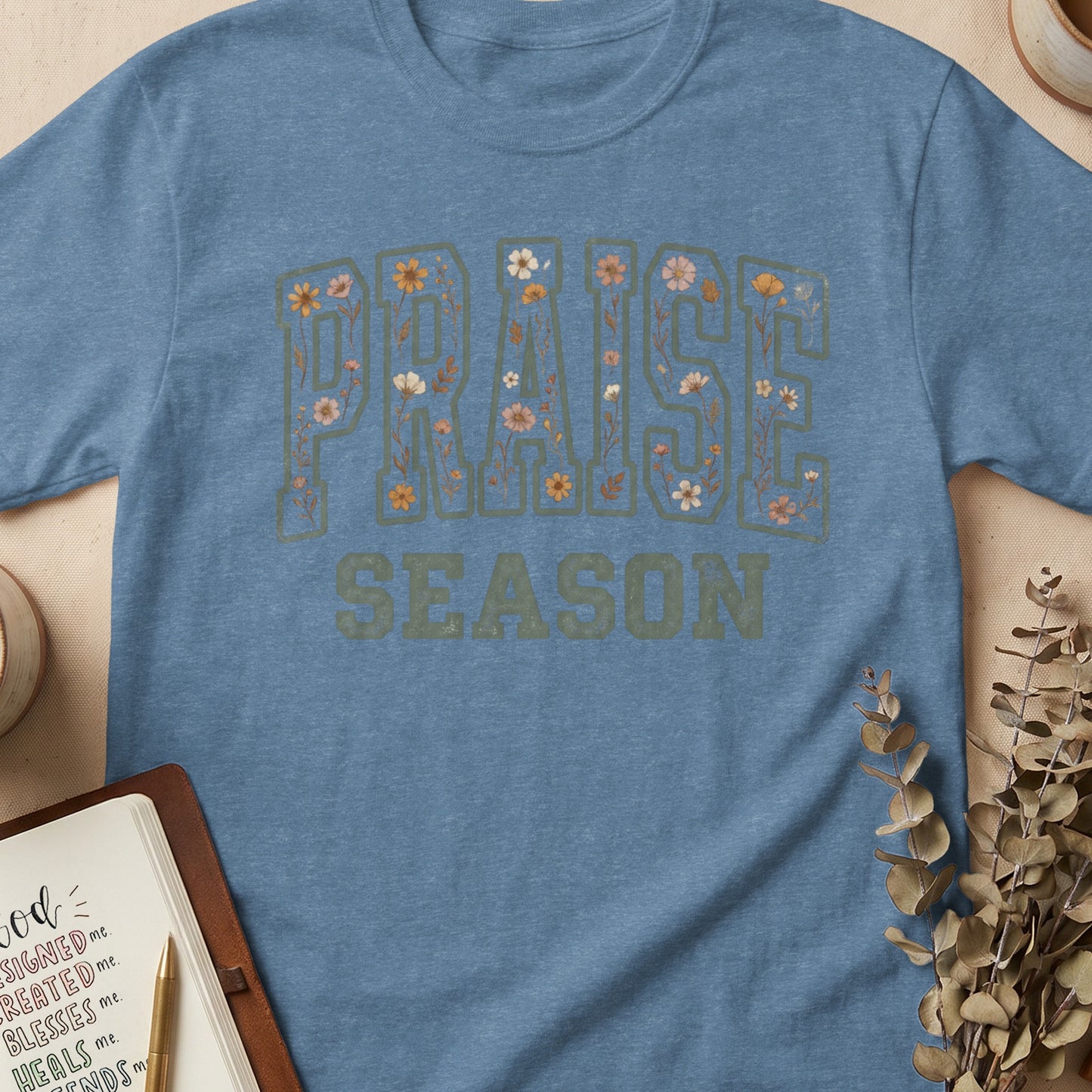Blue t-shirt with floral "Praise Season" graphic and notebook.