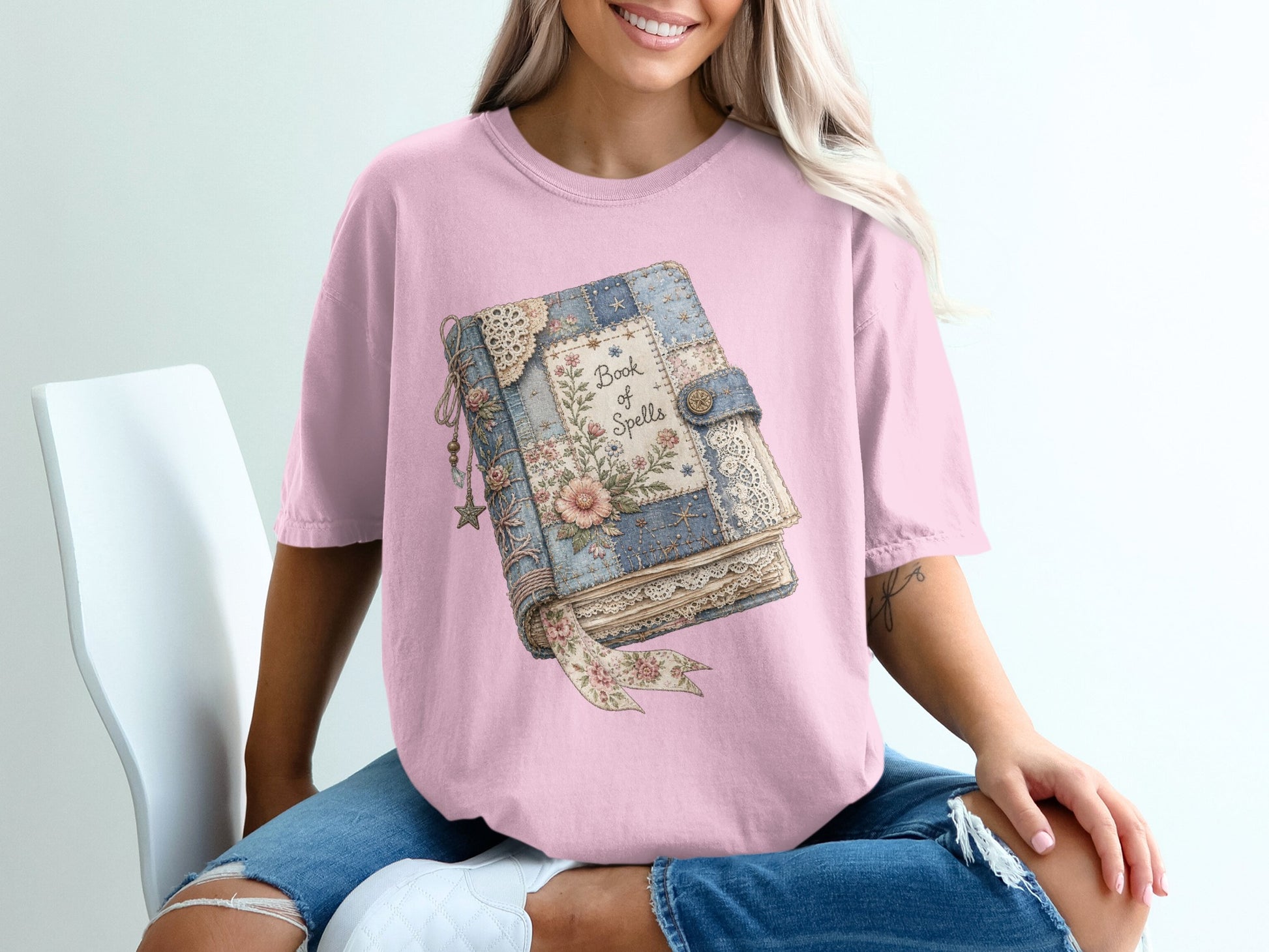 Pink t-shirt with a vintage spellbook graphic featuring floral and lace details.