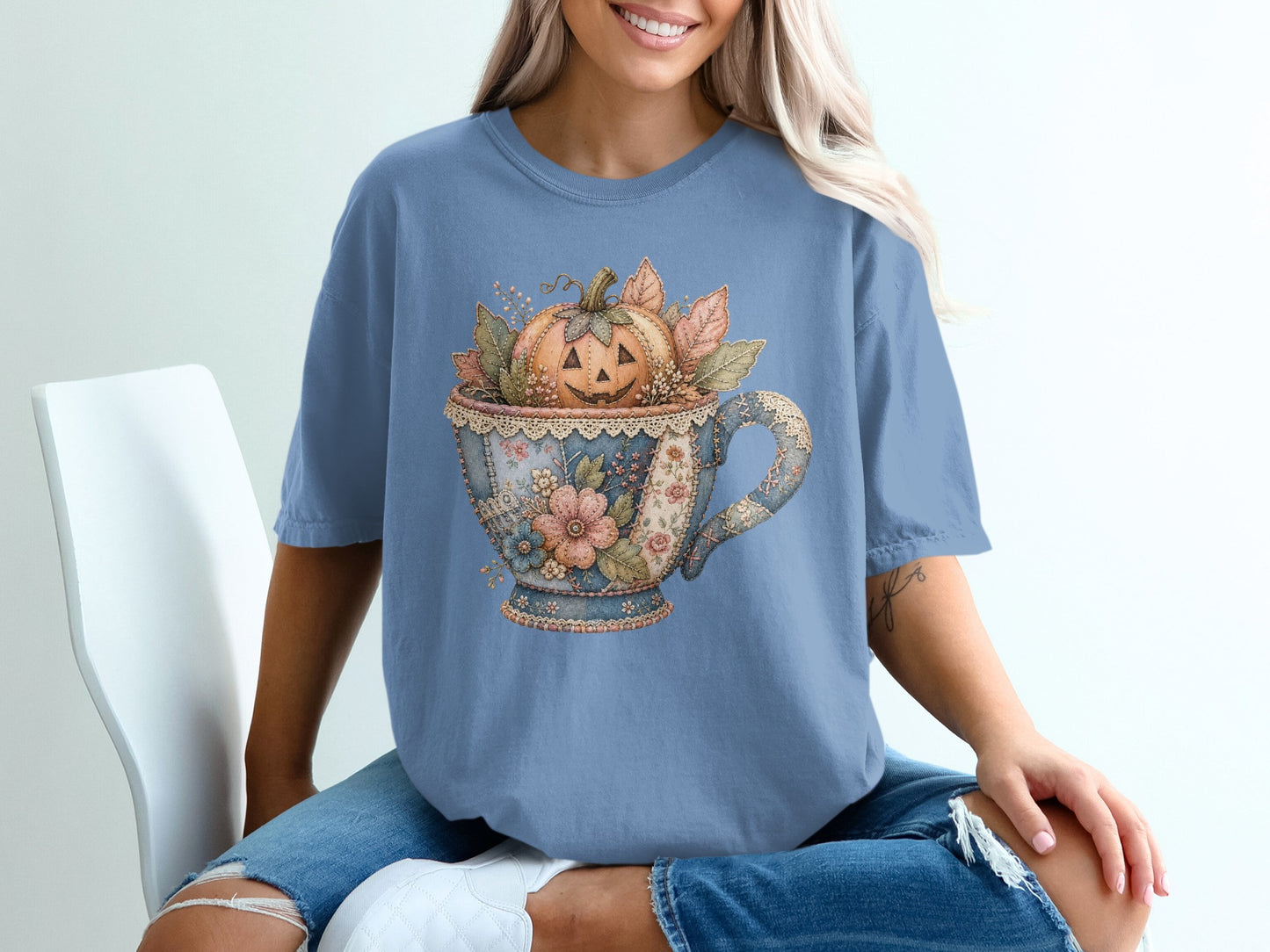 Blue t-shirt with a vintage teacup design featuring a carved jack-o'-lantern and autumn leaves.