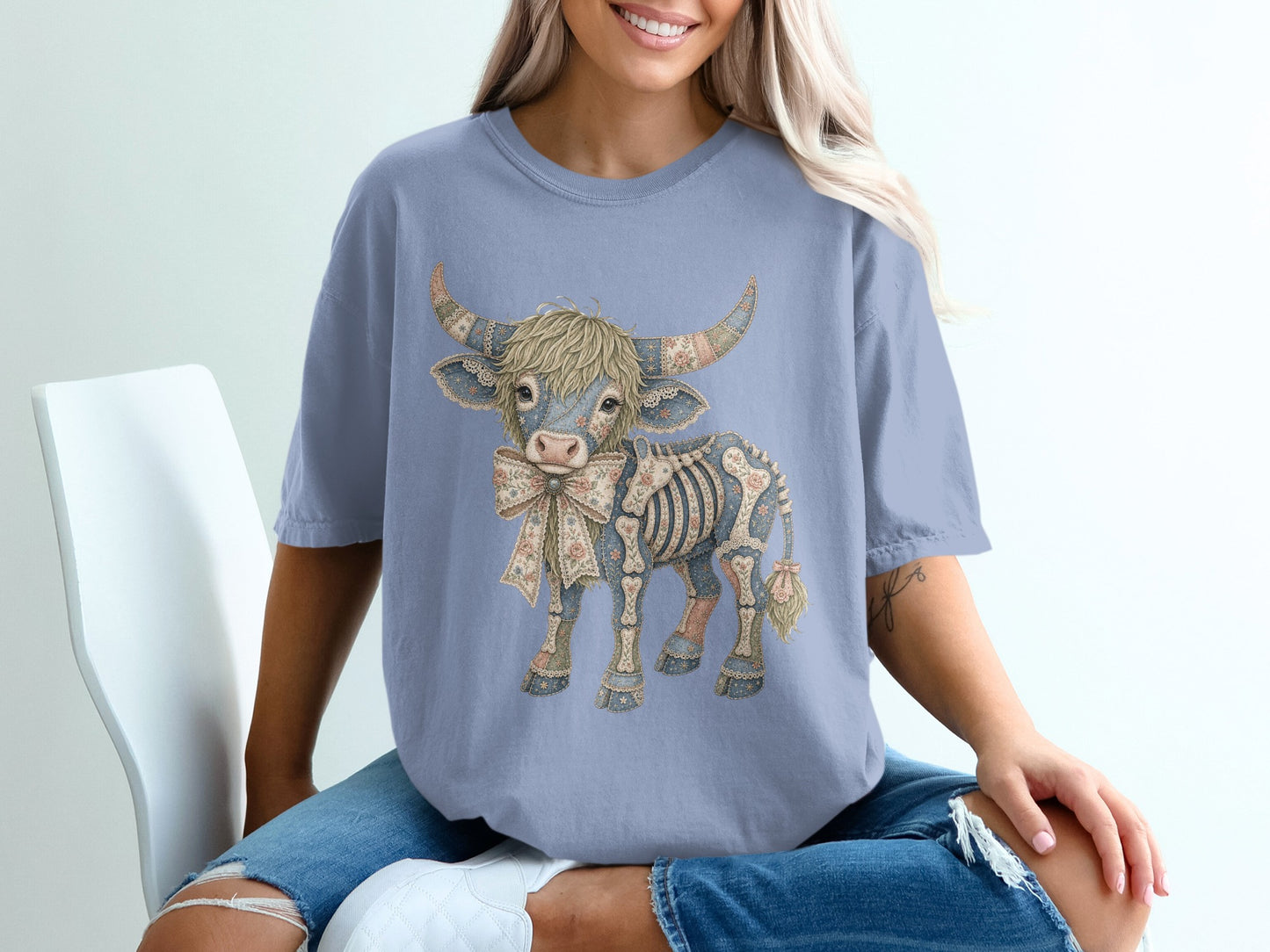 Blue t-shirt with skeleton Highland cow graphic wearing a floral bow.