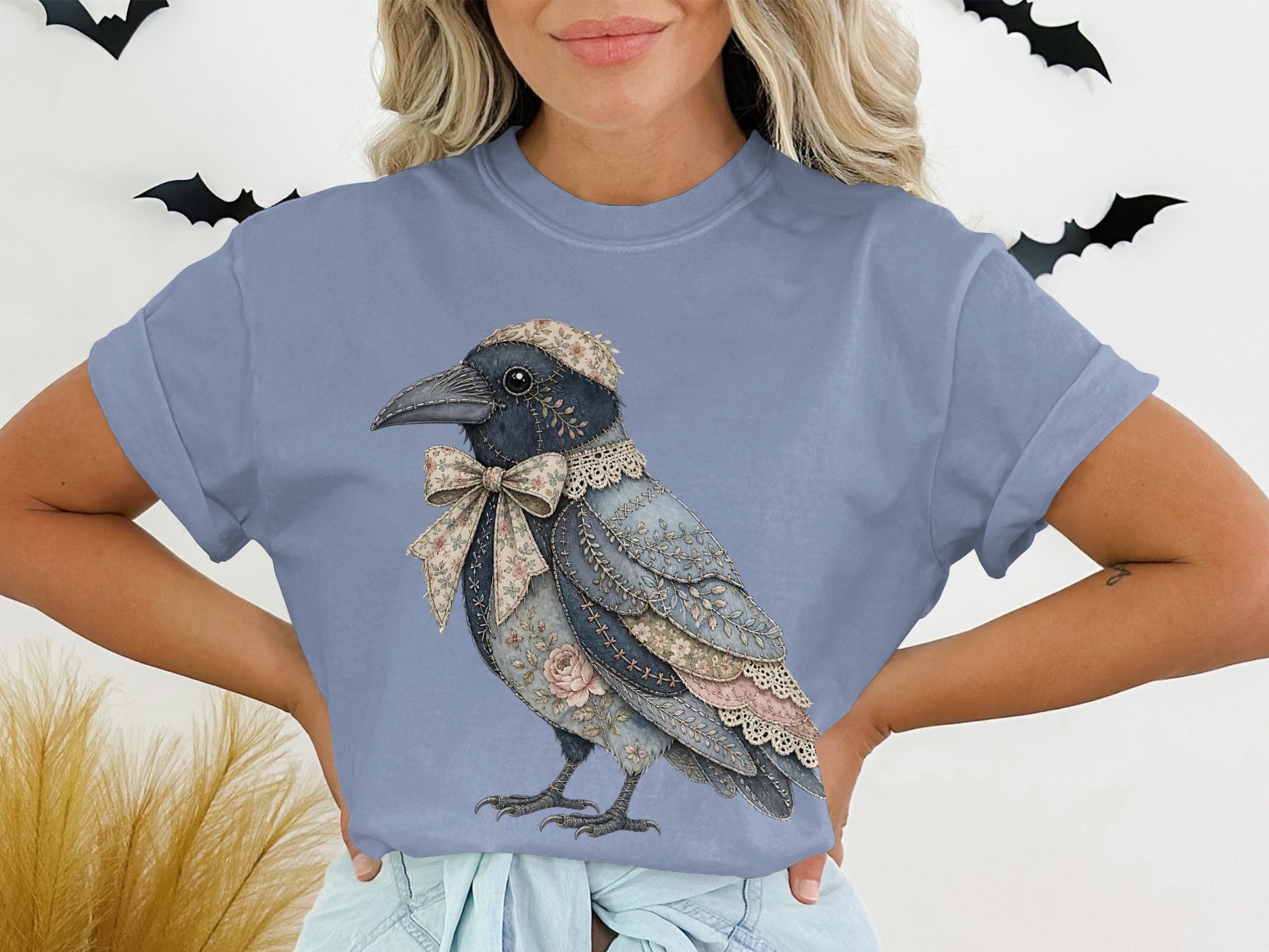 Textured crow graphic with floral bow and lace collar on a blue t-shirt.