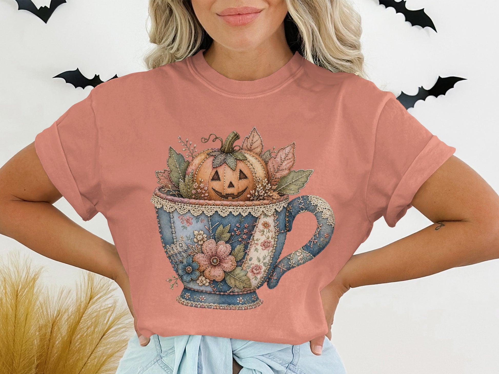 T-shirt with a watercolor graphic of a teacup filled with a pumpkin and autumn leaves.