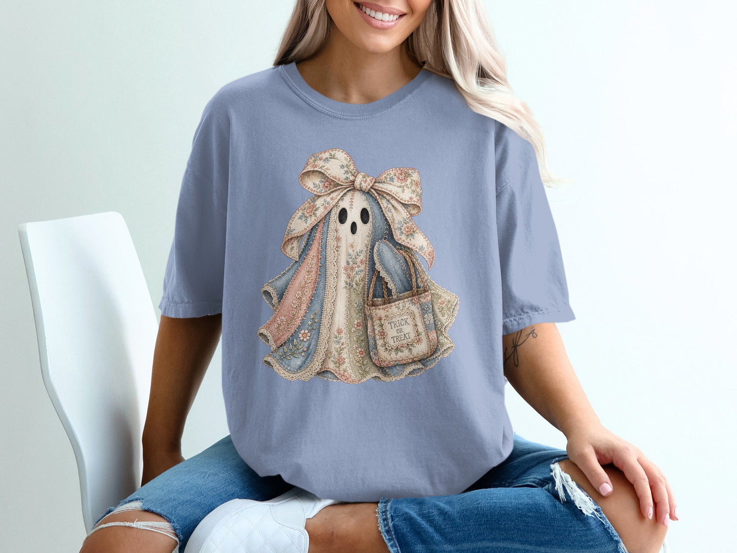 Ghost graphic with floral bow and "Trick or Treat" bag on a light blue t-shirt.